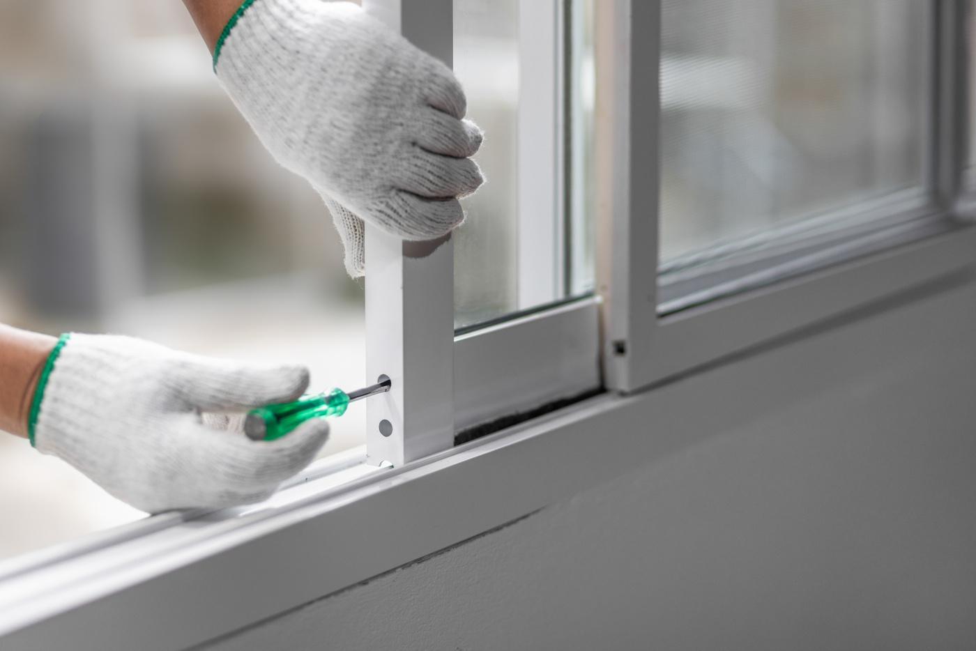 Construction worker repairing the sliding window. Open cap of adjust rail wheel.